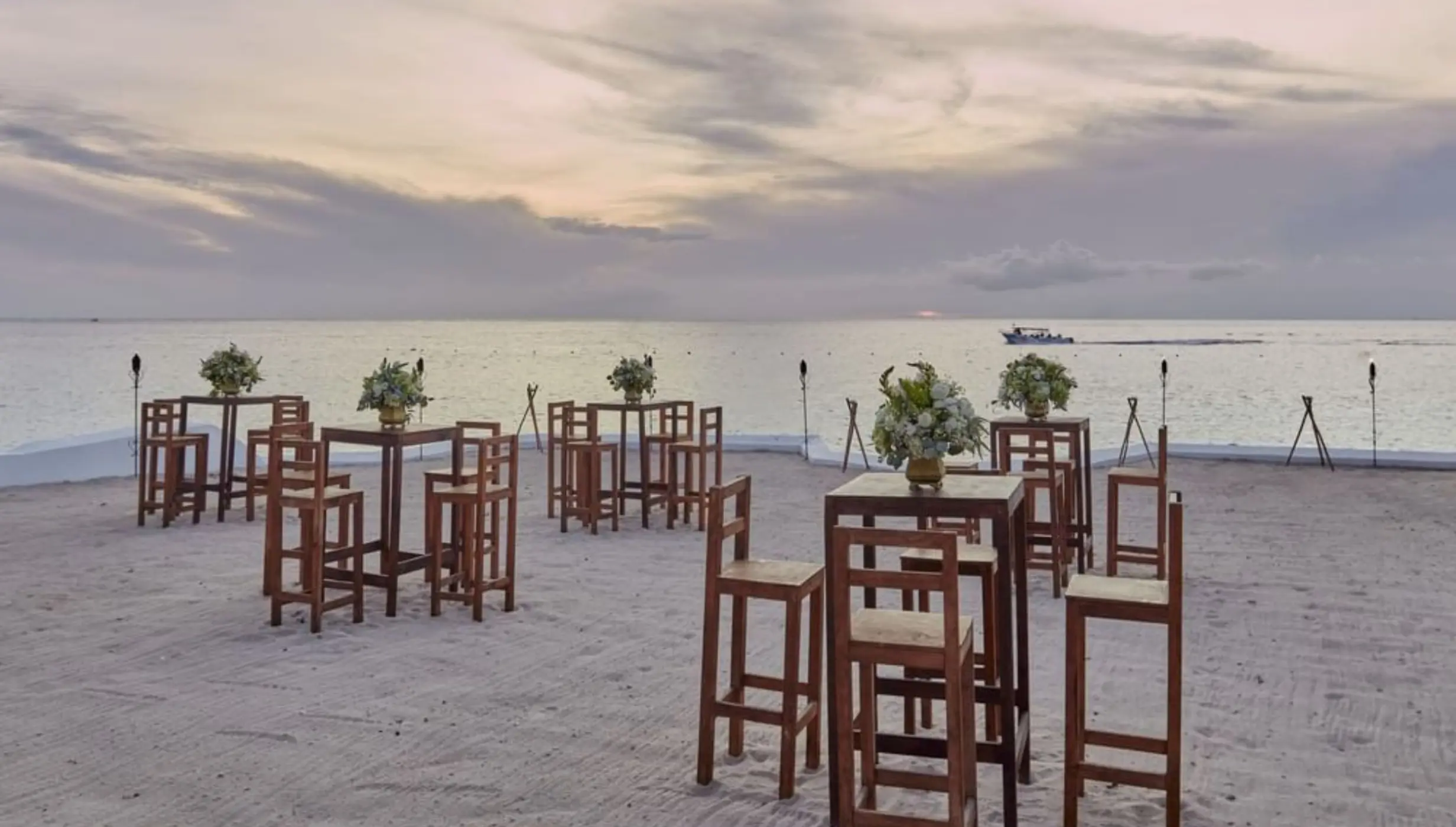 Beach club wedding reception setup with wooden high-top tables at Fiesta Americana Cozumel