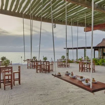 Outdoor wedding reception at Fiesta Americana Cozumel featuring hanging swing tables on the beach
