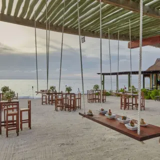 Outdoor wedding reception at Fiesta Americana Cozumel featuring hanging swing tables on the beach