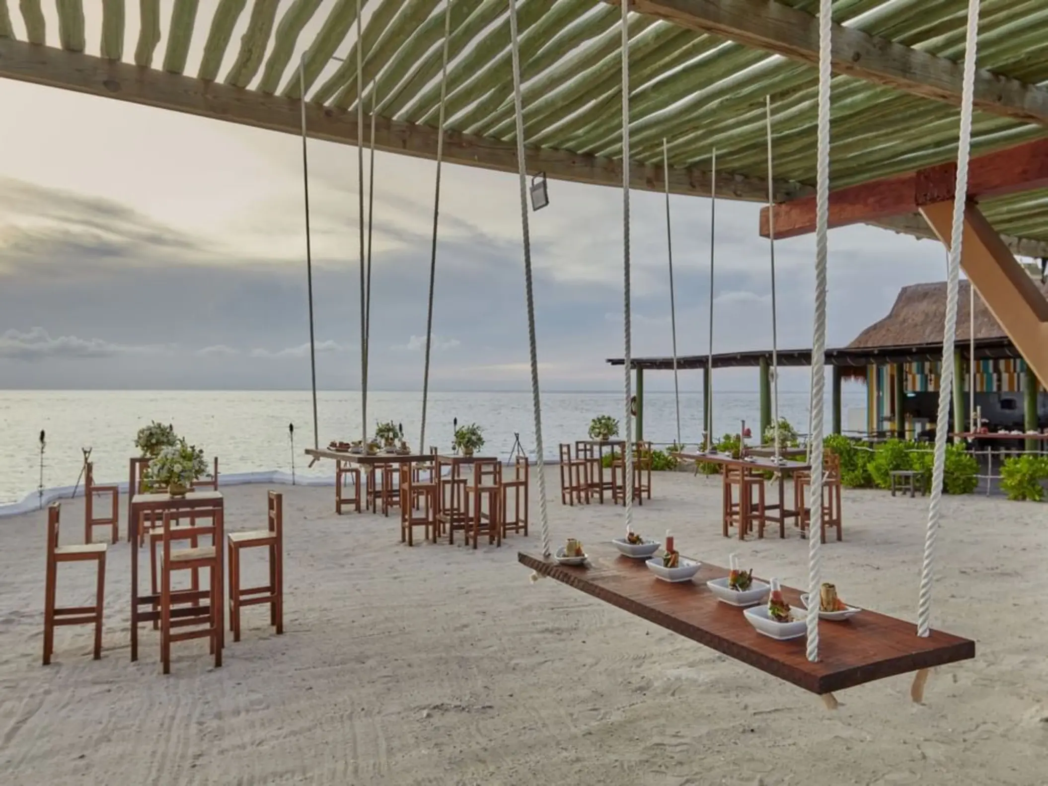 Outdoor wedding reception at Fiesta Americana Cozumel featuring hanging swing tables on the beach
