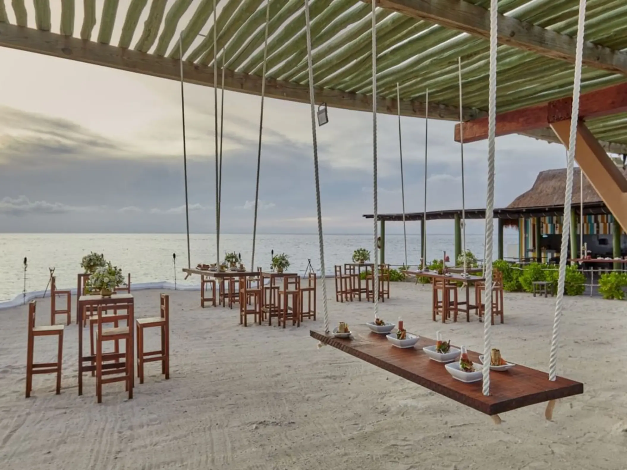 Outdoor wedding reception at Fiesta Americana Cozumel featuring hanging swing tables on the beach