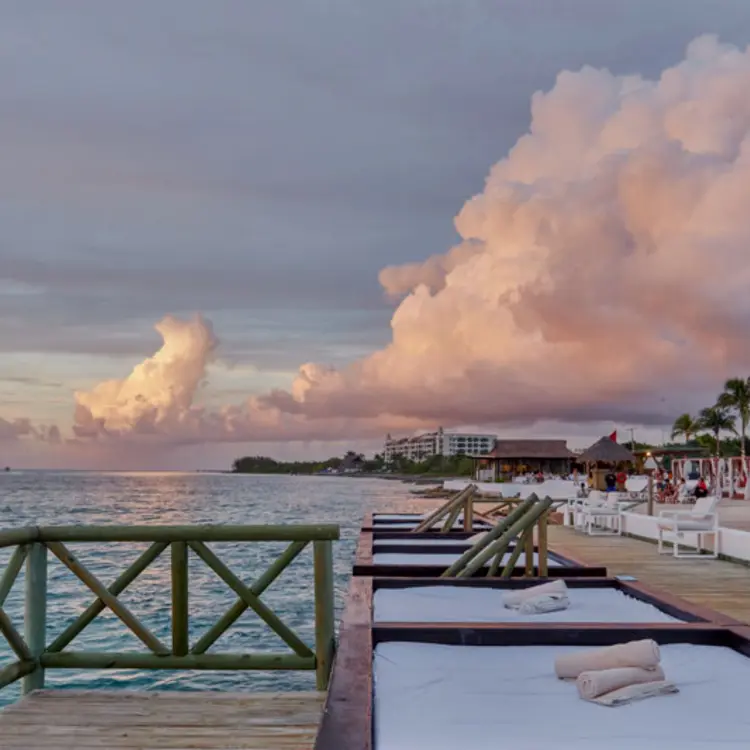 Wooden deck with daybeds at Fiesta Americana Cozumel overlooking the ocean at sunset