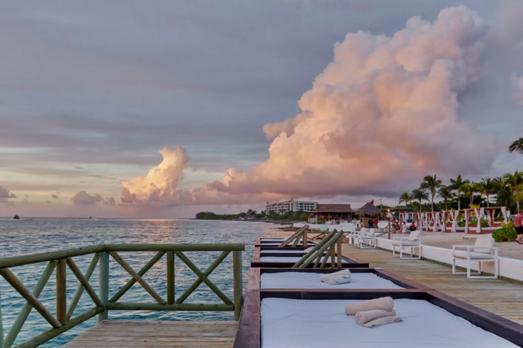 Wooden deck with daybeds at Fiesta Americana Cozumel overlooking the ocean at sunset