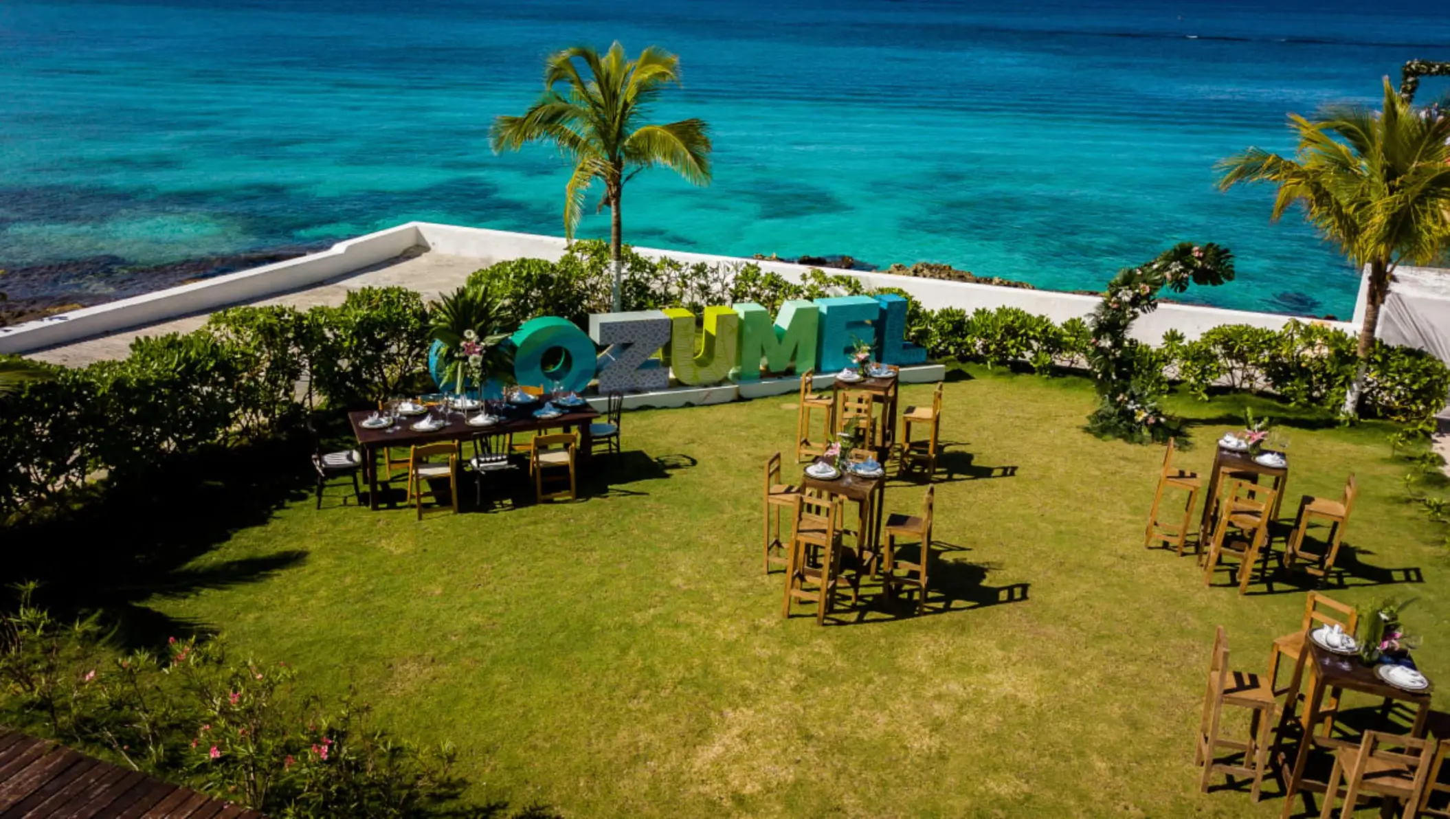 Outdoor wedding reception with wood tables and ocean views at Fiesta Americana Cozumel