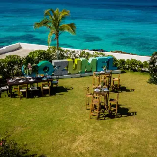 Outdoor wedding reception with wood tables and ocean views at Fiesta Americana Cozumel