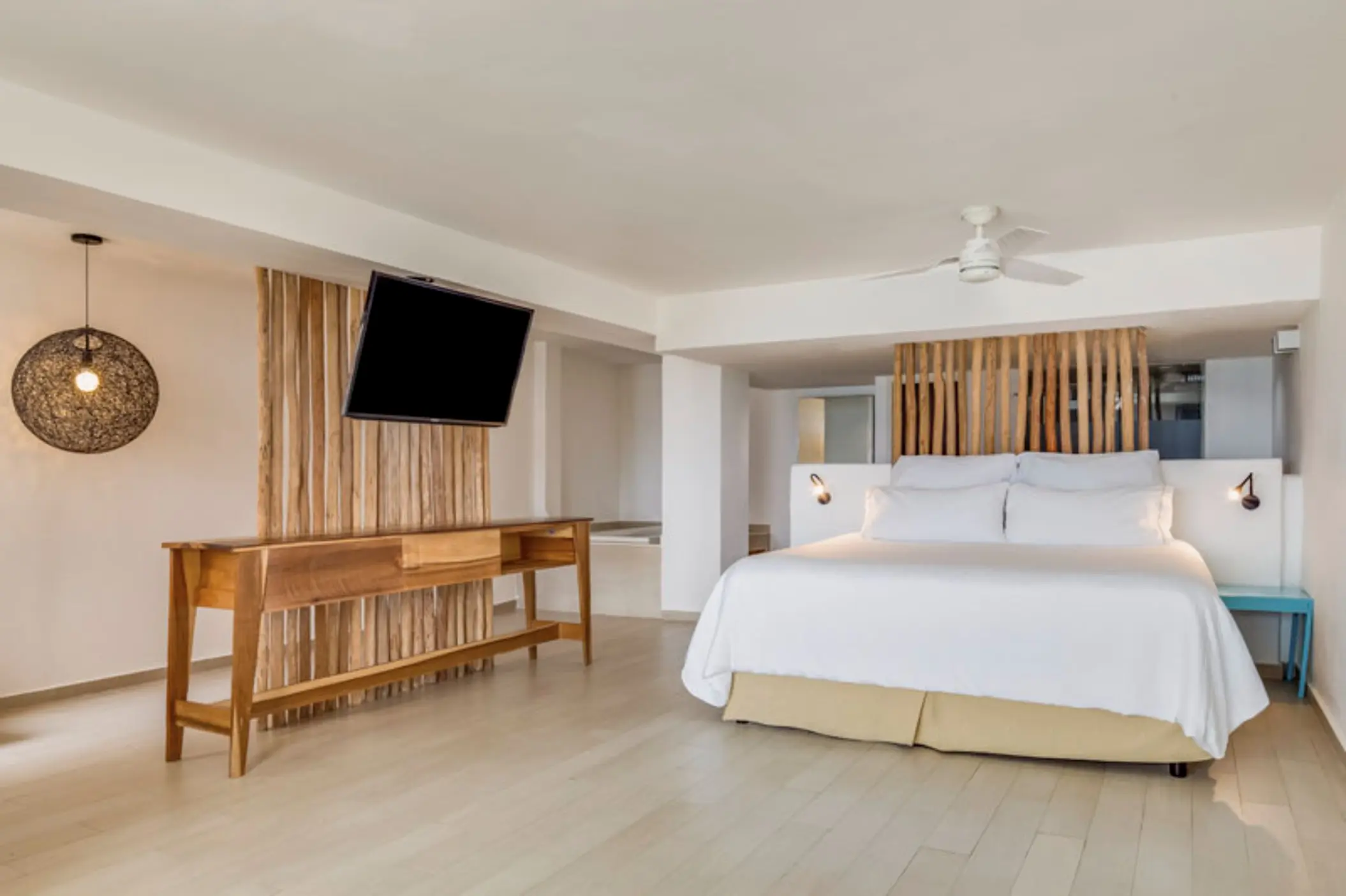 Honeymoon suite with wood accents and a white king bed at Fiesta Americana Cozumel