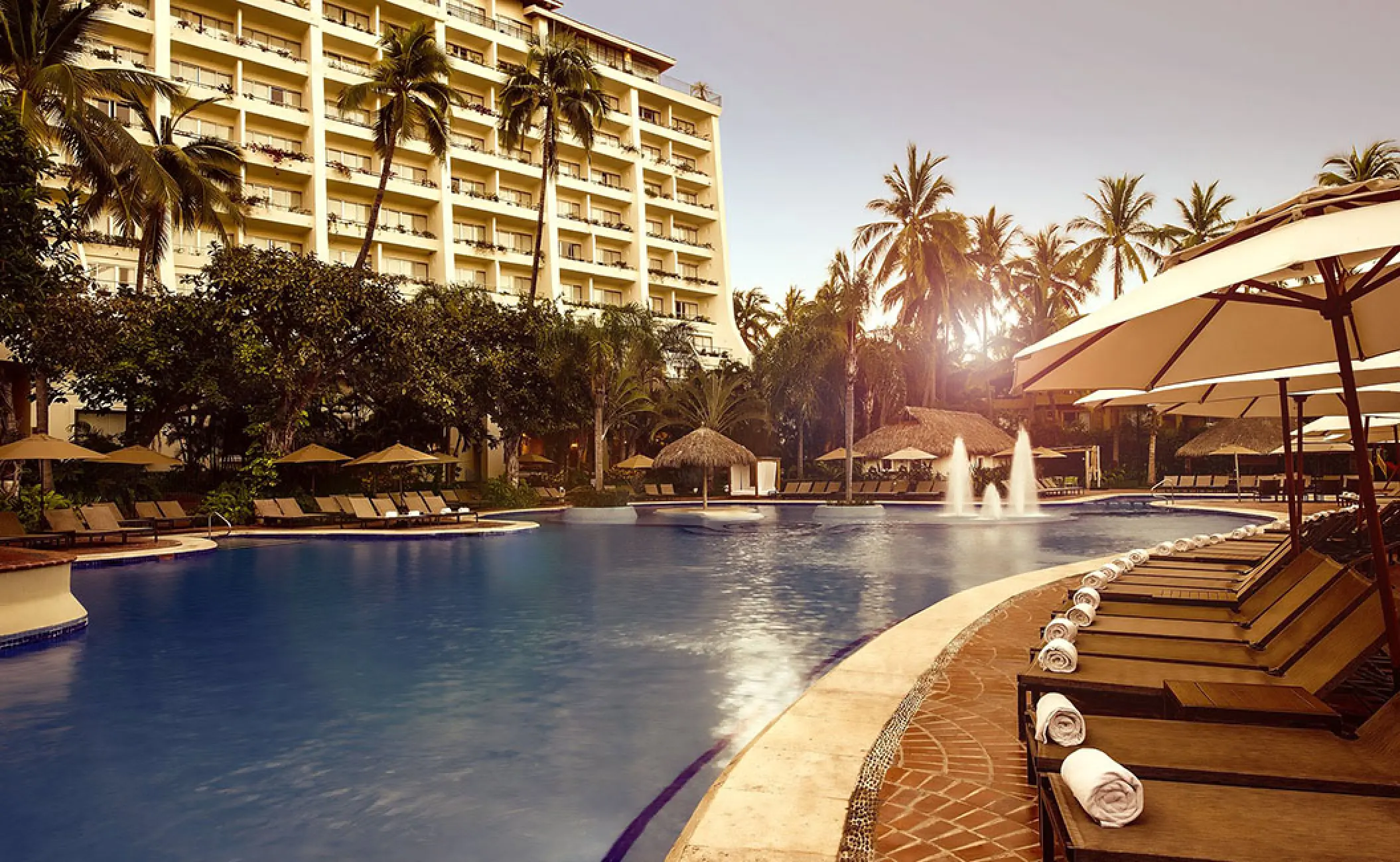 Fiesta Americana Puerto Vallarta pool area with lounge chairs and water fountains at sunrise, Puerto Vallarta