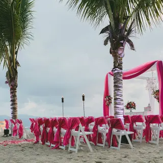 Beachfront wedding ceremony with pink draped chairs and arch at Fiesta Americana Puerto Vallarta