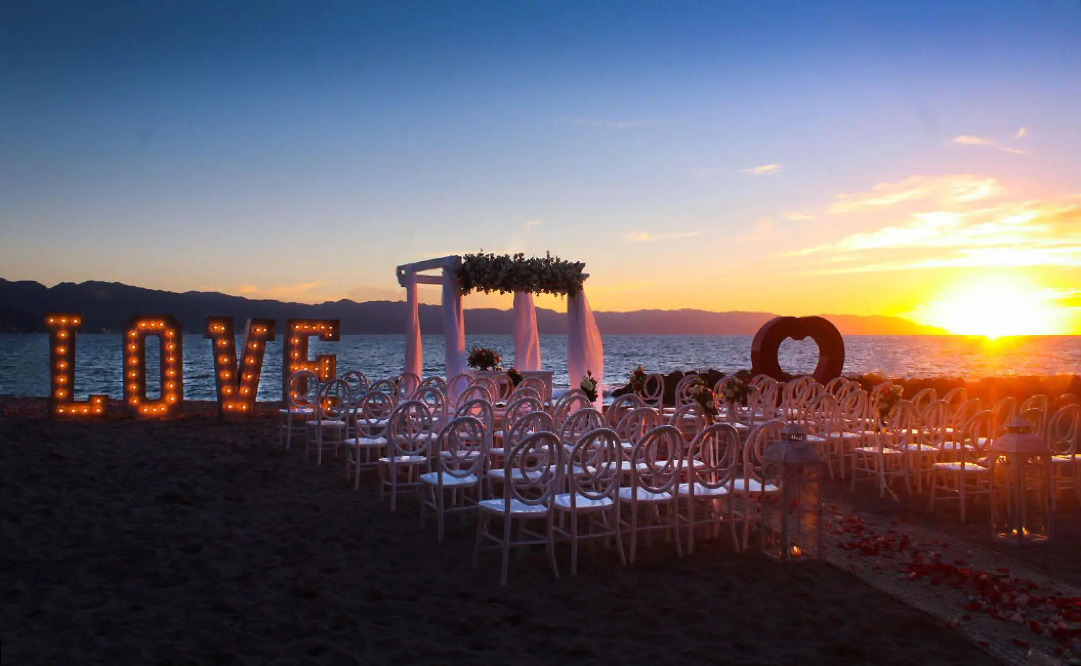 Beachfront wedding ceremony with lighted LOVE sign at sunset, Fiesta Americana Puerto Vallarta
