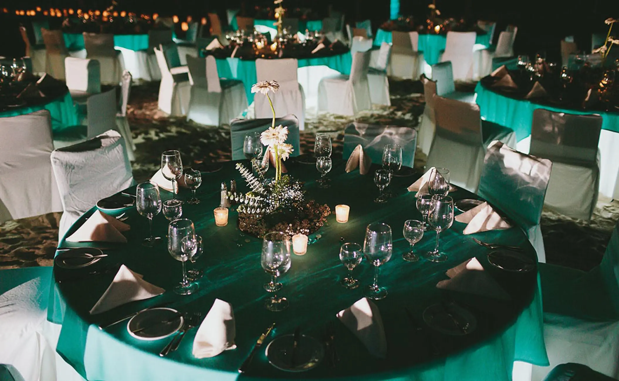 Indoor wedding reception setup with teal linens and candlelight at Fiesta Americana Puerto Vallarta