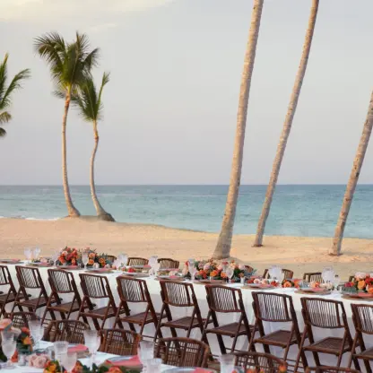 Beachfront wedding reception setup with long tables and palm trees at Finest Punta Cana, Punta Cana