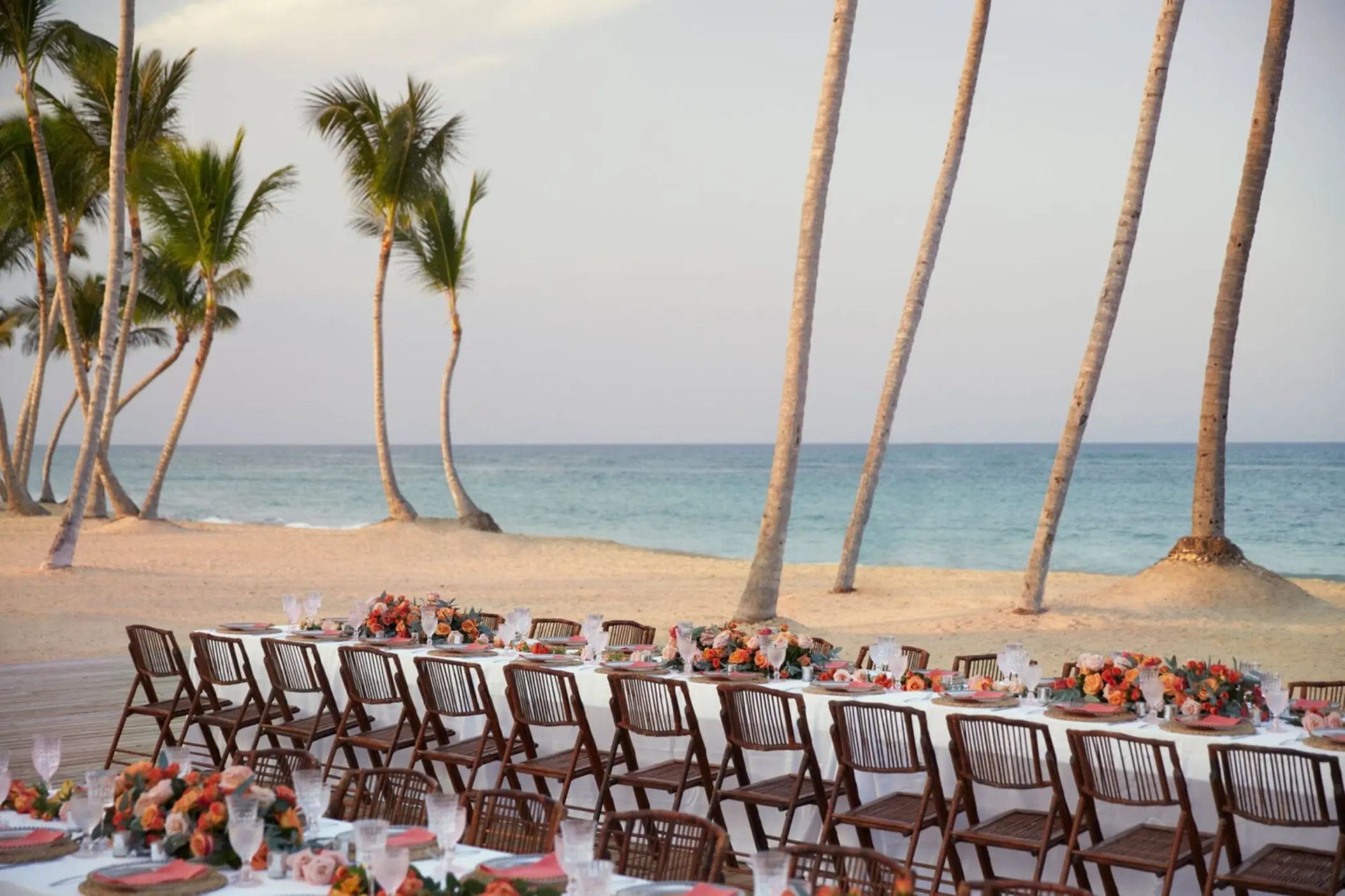 Beachfront wedding reception setup with long tables and palm trees at Finest Punta Cana, Punta Cana