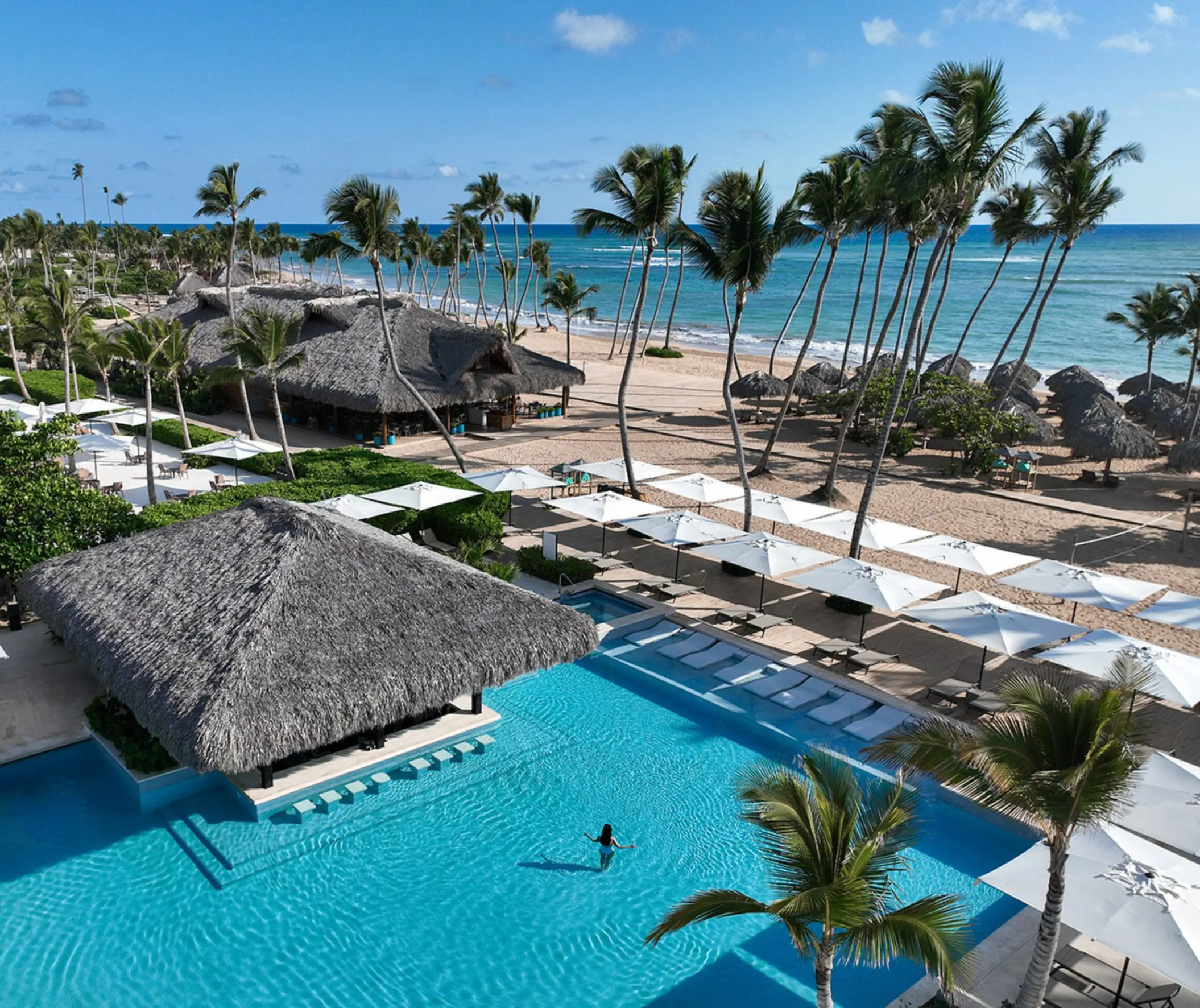 Finest Punta Cana swimming pool and beachfront with palm trees and palapas, Punta Cana