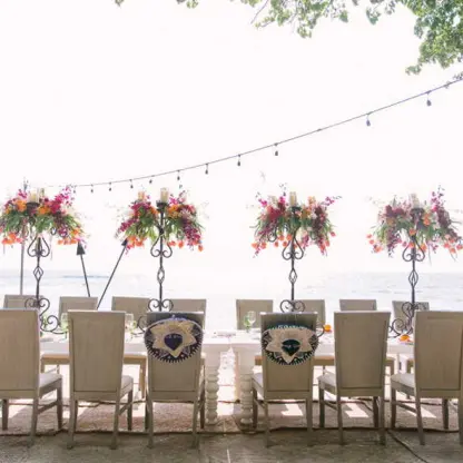 Beachfront wedding reception setup with floral centerpieces and string lights at Four Seasons Punta Mita