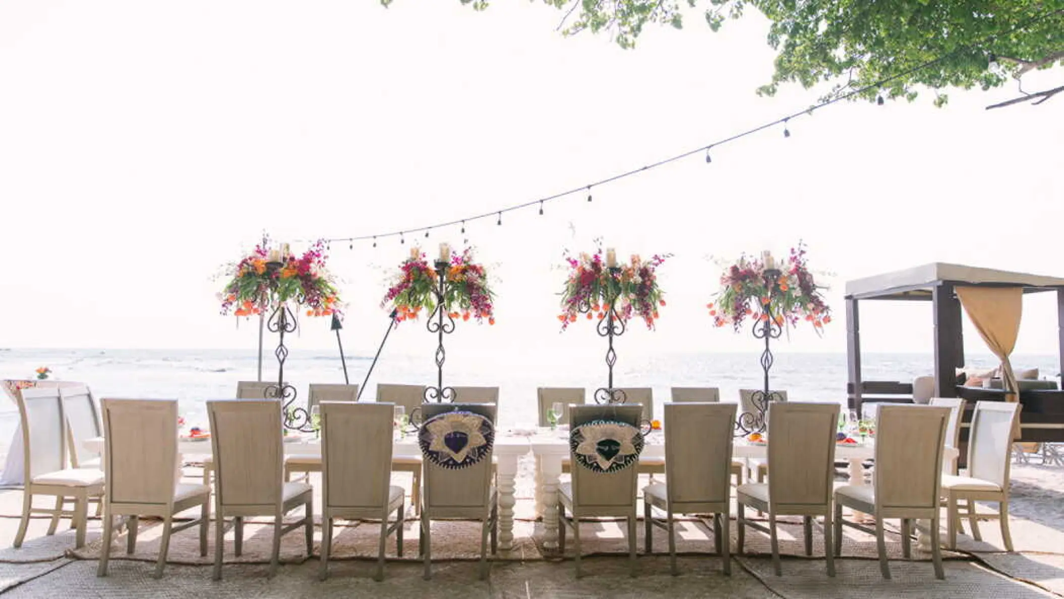 Beachfront wedding reception setup with floral centerpieces and string lights at Four Seasons Punta Mita