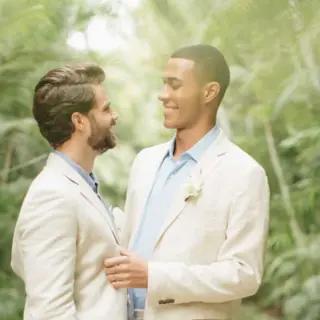 Grooms in white suits smiling at each other at Four Seasons Punta Mita