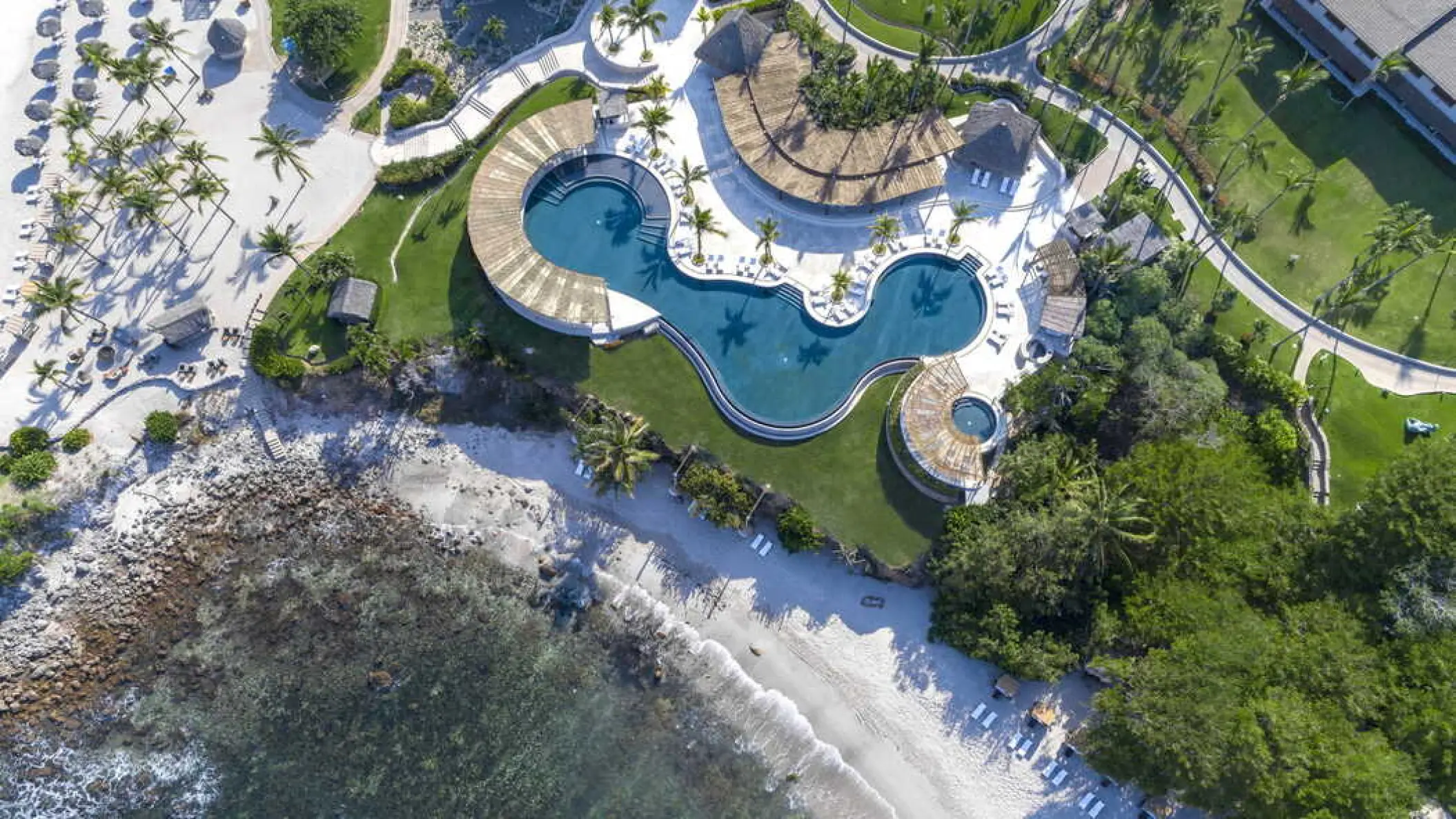 Aerial view of the curved swimming pool and beachfront at Four Seasons Punta Mita