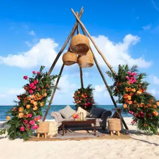 Tipi wedding lounge setup with floral arrangements on the beach at Garza Blanca Cancun