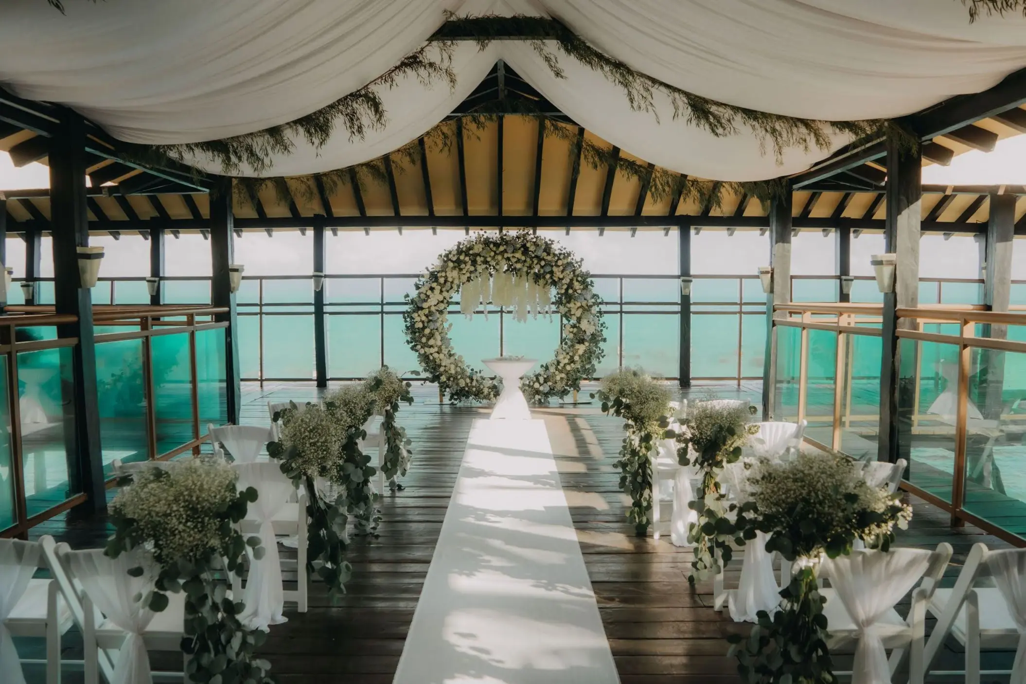 Pier wedding ceremony setup with floral hoop at Generations Riviera Maya