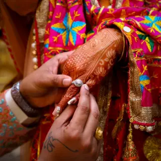 Close-up of a groom placing a ring on the bride's henna-patterned hand at Grand Bavaro Princess, Punta Cana