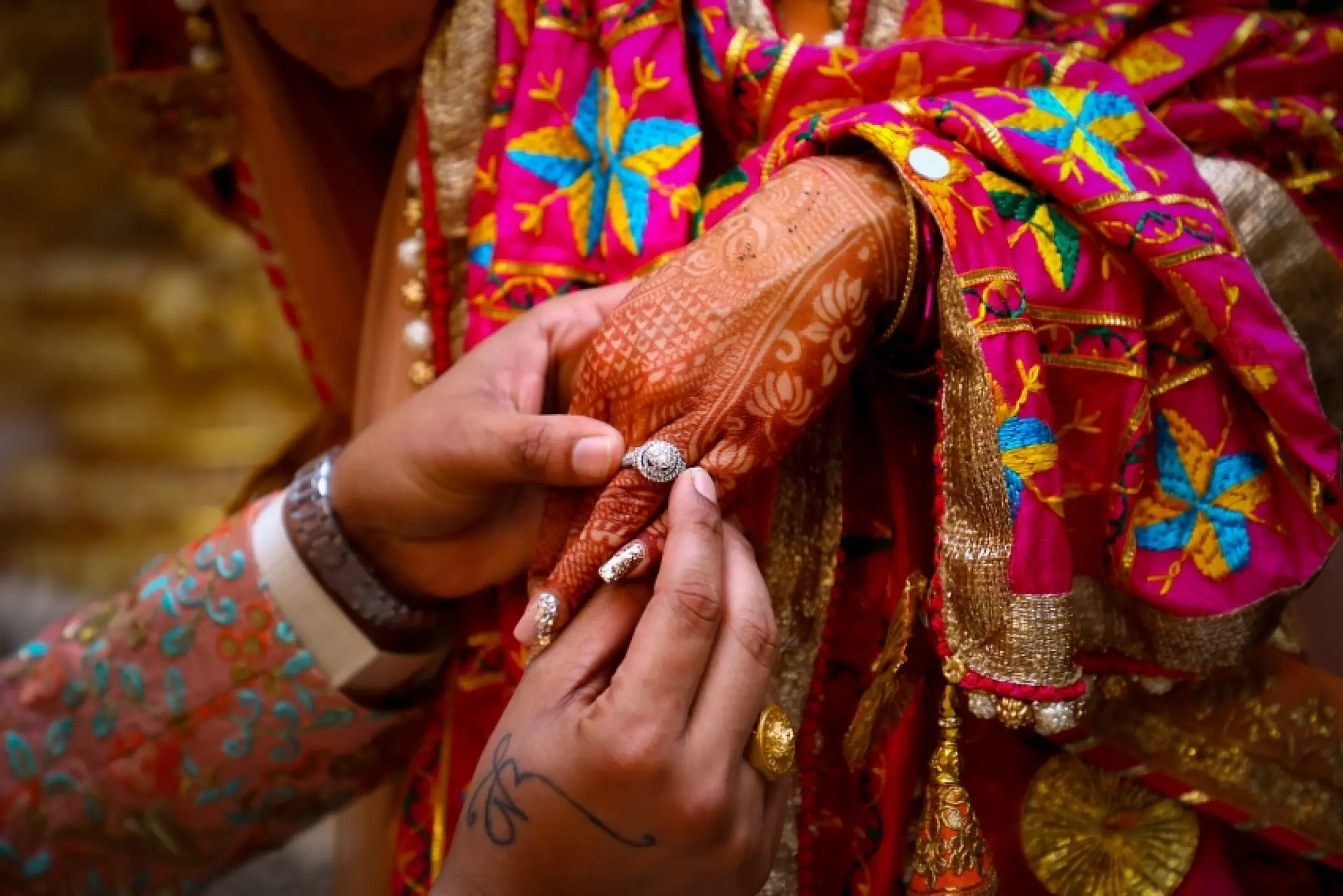 Close-up of a groom placing a ring on the bride's henna-patterned hand at Grand Bavaro Princess, Punta Cana