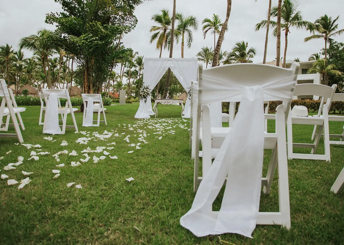 Tropical garden wedding ceremony with white chairs and floral petals at Grand Bavaro Princess, Punta Cana