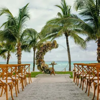 Sunrise Terrace wedding ceremony with floral arch and wooden chairs at Grand Fiesta Americana Coral Beach, Cancun