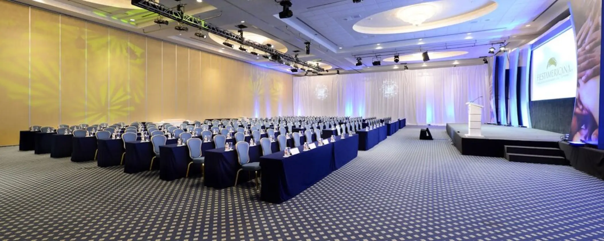 Grand Fiesta Americana Coral Beach ballroom setup with blue draped tables and stage, Cancun