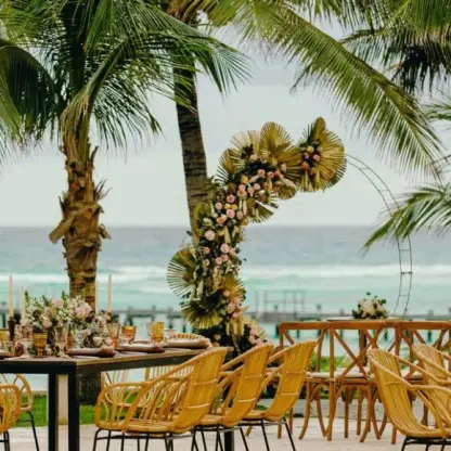 Outdoor wedding reception setup with wicker chairs and floral arch at Grand Fiesta Americana Coral Beach, Cancun