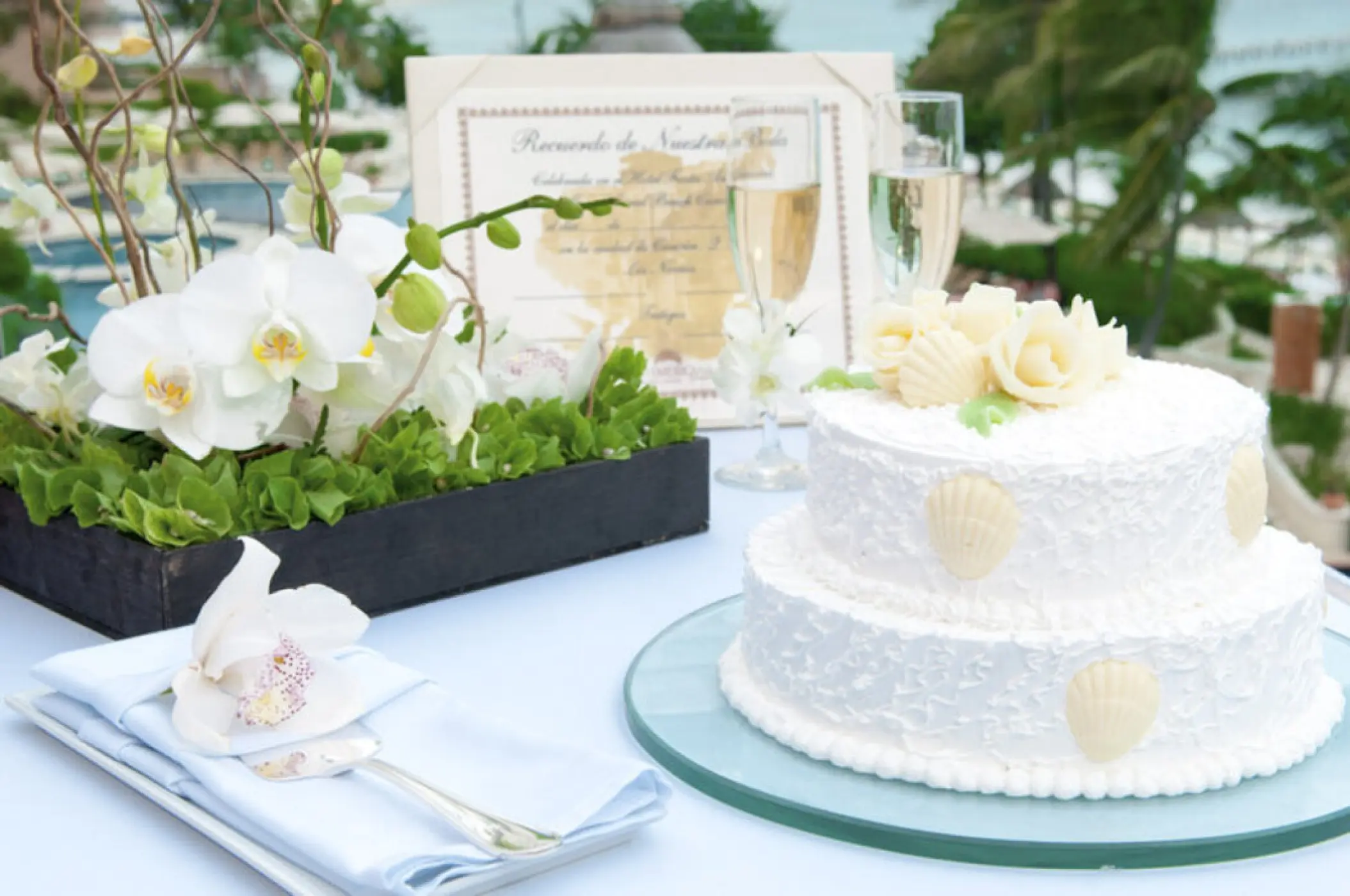White tiered wedding cake with seashell decor at Grand Fiesta Americana Coral Beach, Cancun