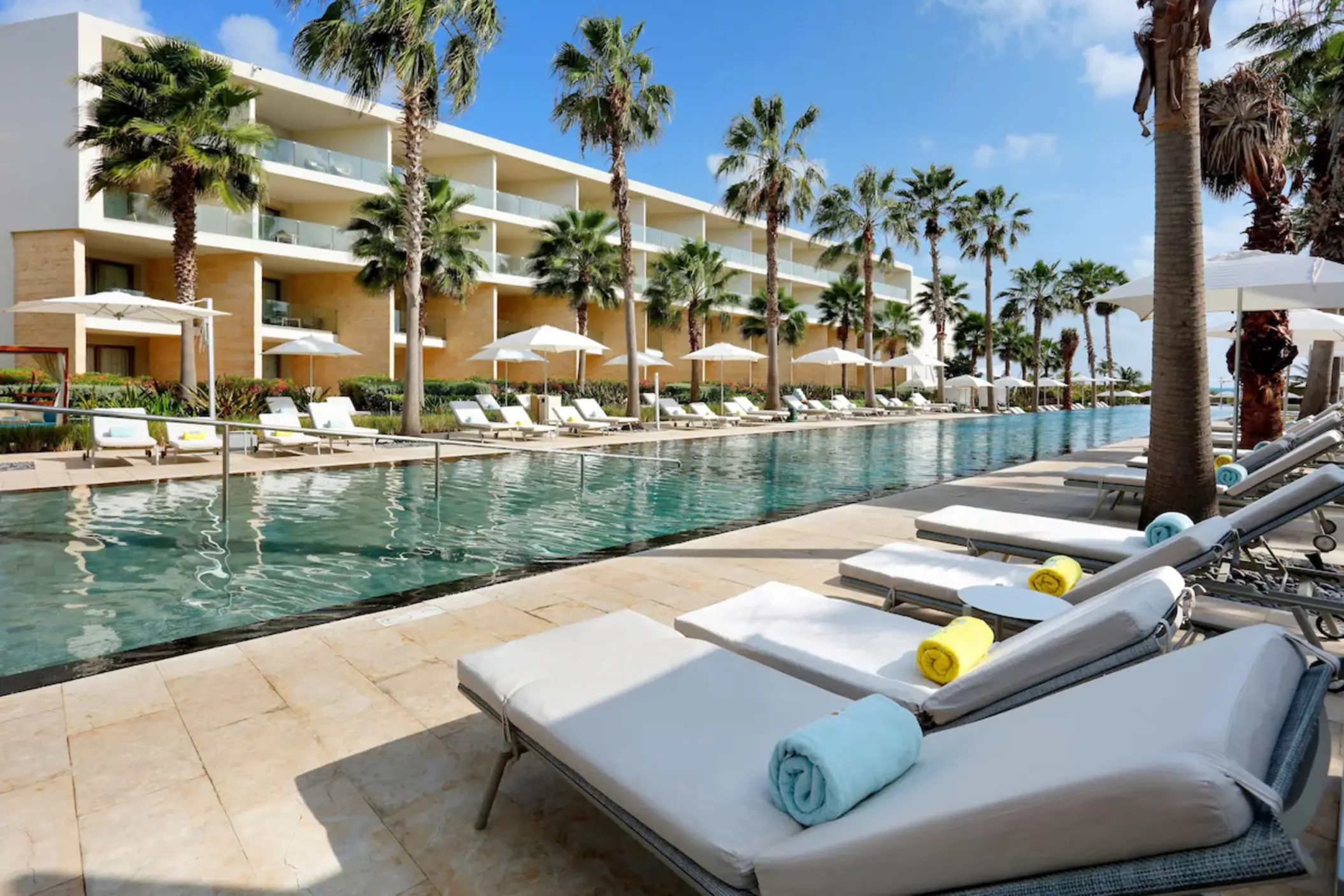 Long pool area with sun loungers and palm trees at Grand Palladium Costa Mujeres, Cancun