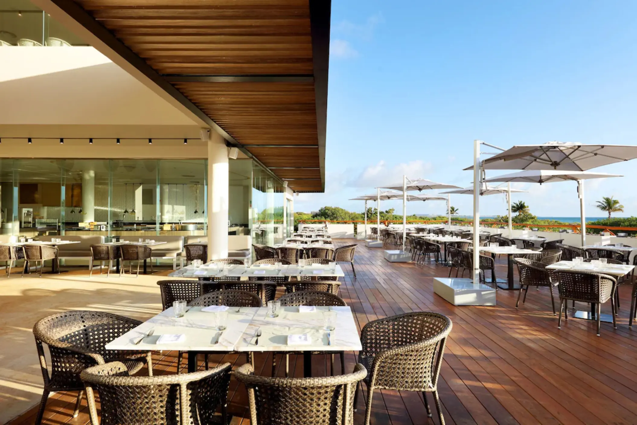Outdoor terrace restaurant with white umbrellas and wooden decking at Grand Palladium Costa Mujeres, Cancun