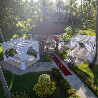 Aerial view of a garden wedding ceremony with a red gazebo and white cabanas at Grand Palladium, Punta Cana
