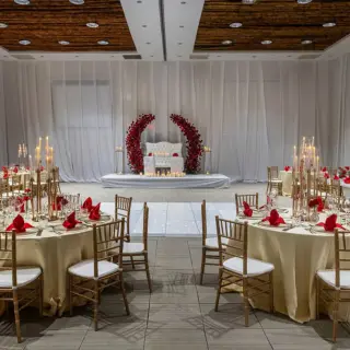 Indoor wedding reception setup with gold chairs and red floral accents at Grand Palladium Punta Cana