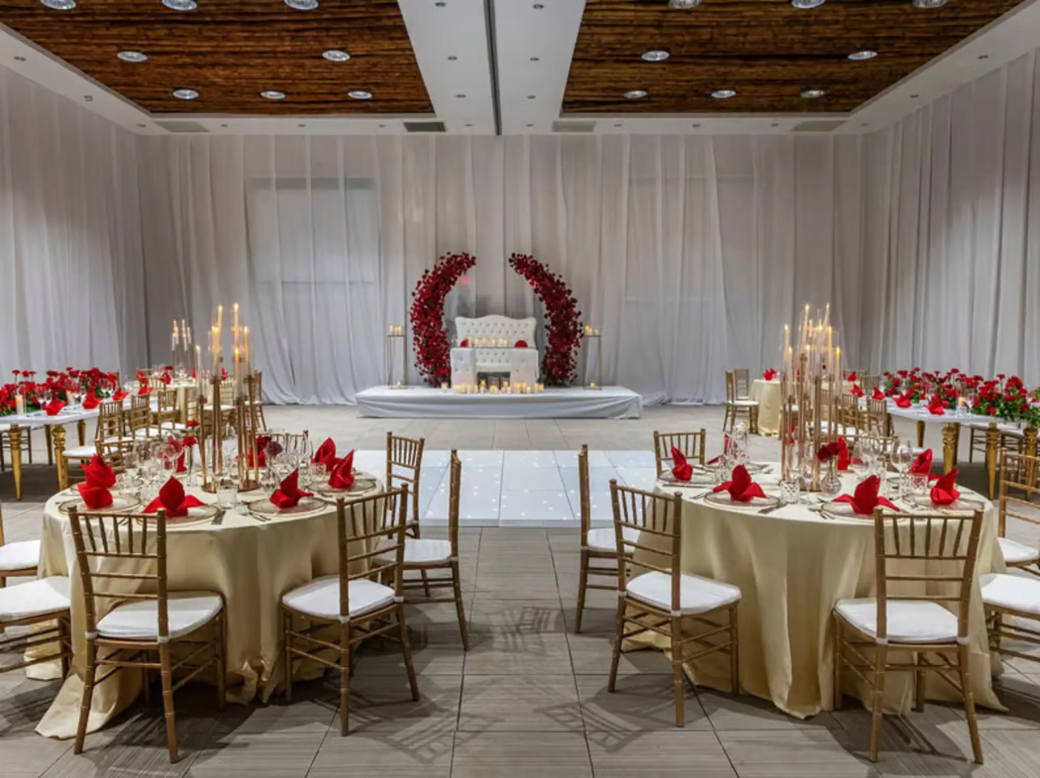 Indoor wedding reception setup with gold chairs and red floral accents at Grand Palladium Punta Cana