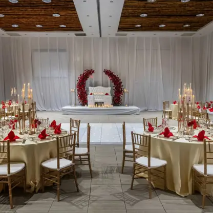 Indoor wedding reception setup with gold chairs and red floral accents at Grand Palladium Punta Cana