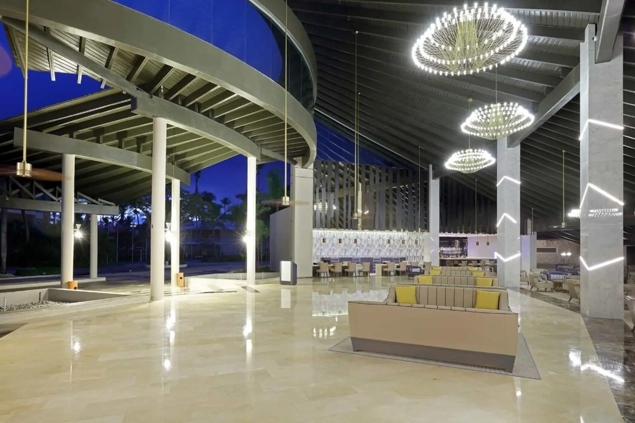 Modern open-air lobby with circular chandeliers and lounge seating at Grand Palladium Punta Cana