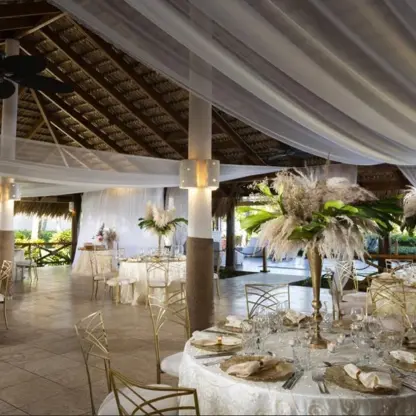 Poseidon Terrace wedding reception under a thatched roof with white draping at Grand Palladium Punta Cana