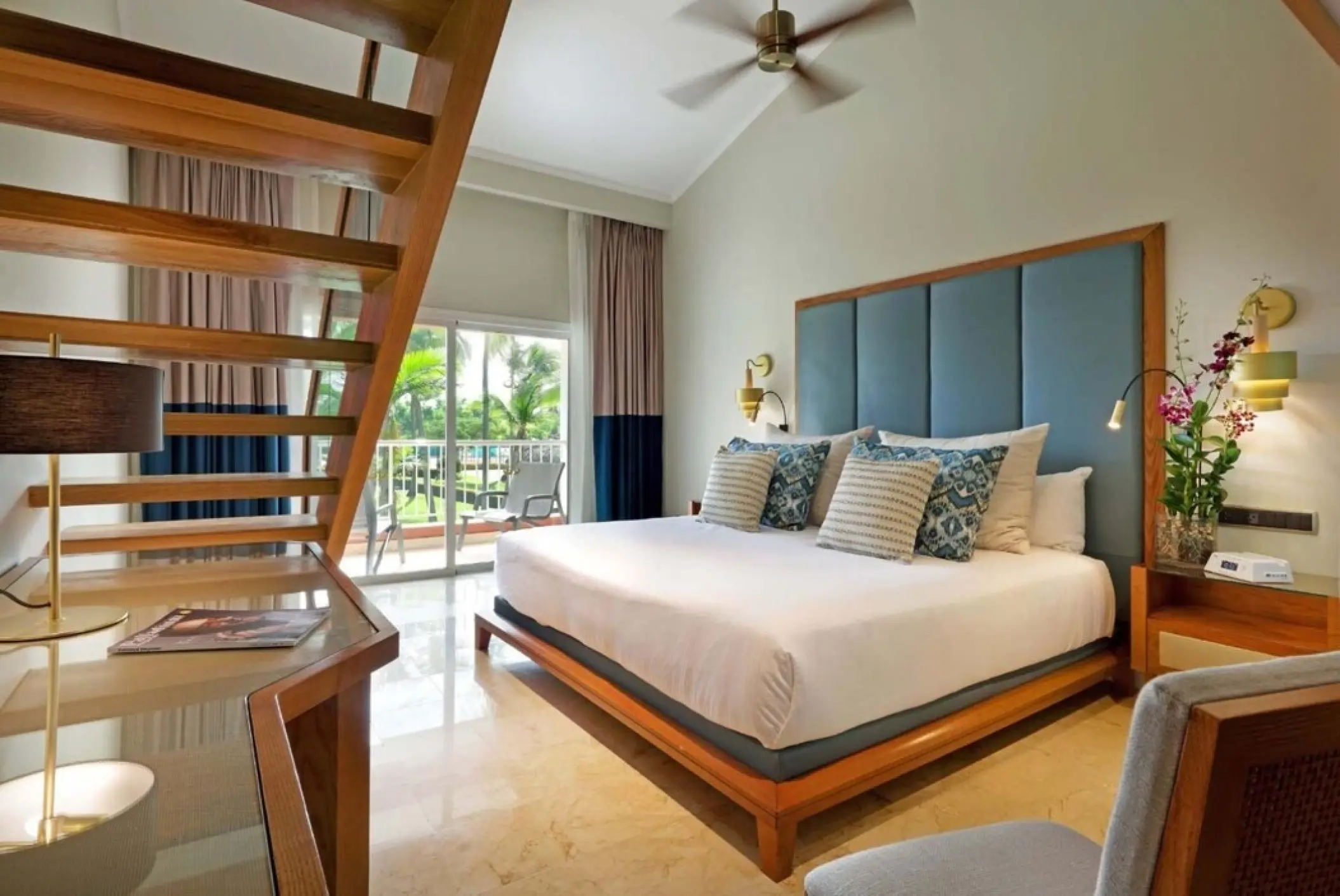 Modern suite with blue headboard and wooden stairs at Grand Palladium Punta Cana