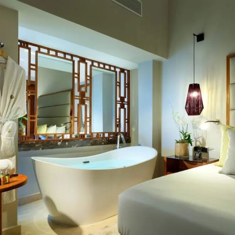 Modern guest suite with a freestanding bathtub and plush bedding at Grand Palladium Punta Cana