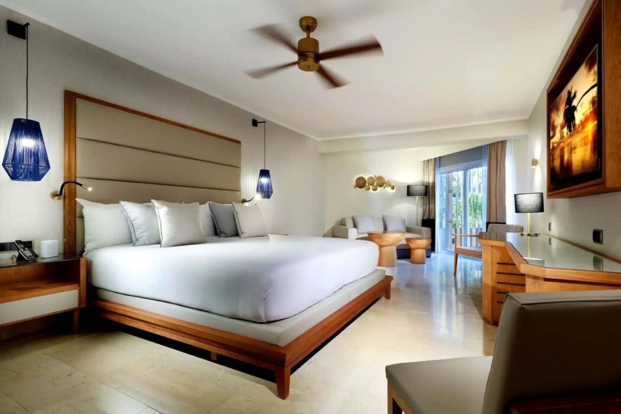 Suite with king bed, seating area, and blue glass pendant lights at Grand Palladium Punta Cana, Punta Cana