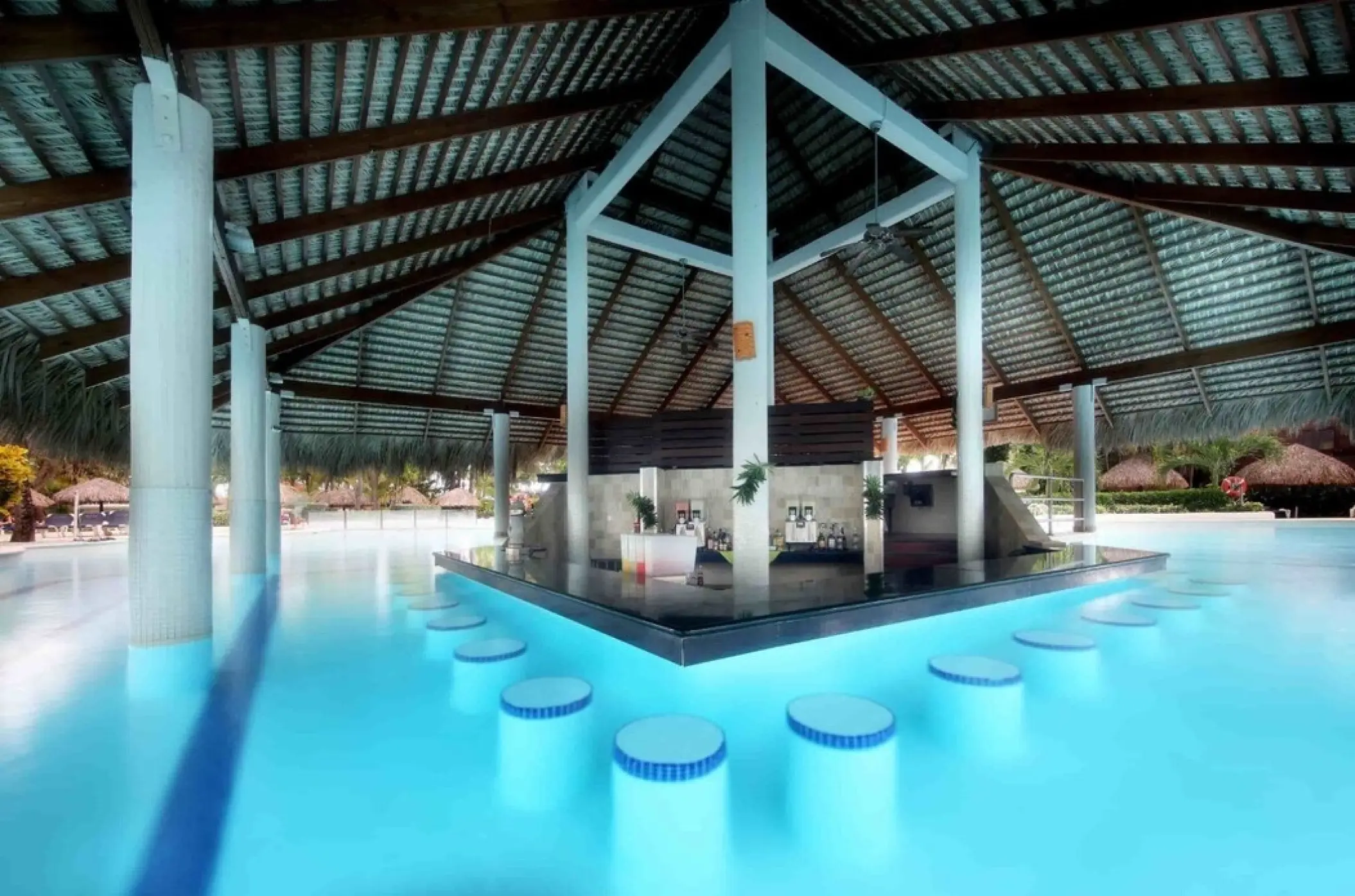 Swim-up bar with submerged stools under a thatched roof at Grand Palladium Punta Cana, Punta Cana