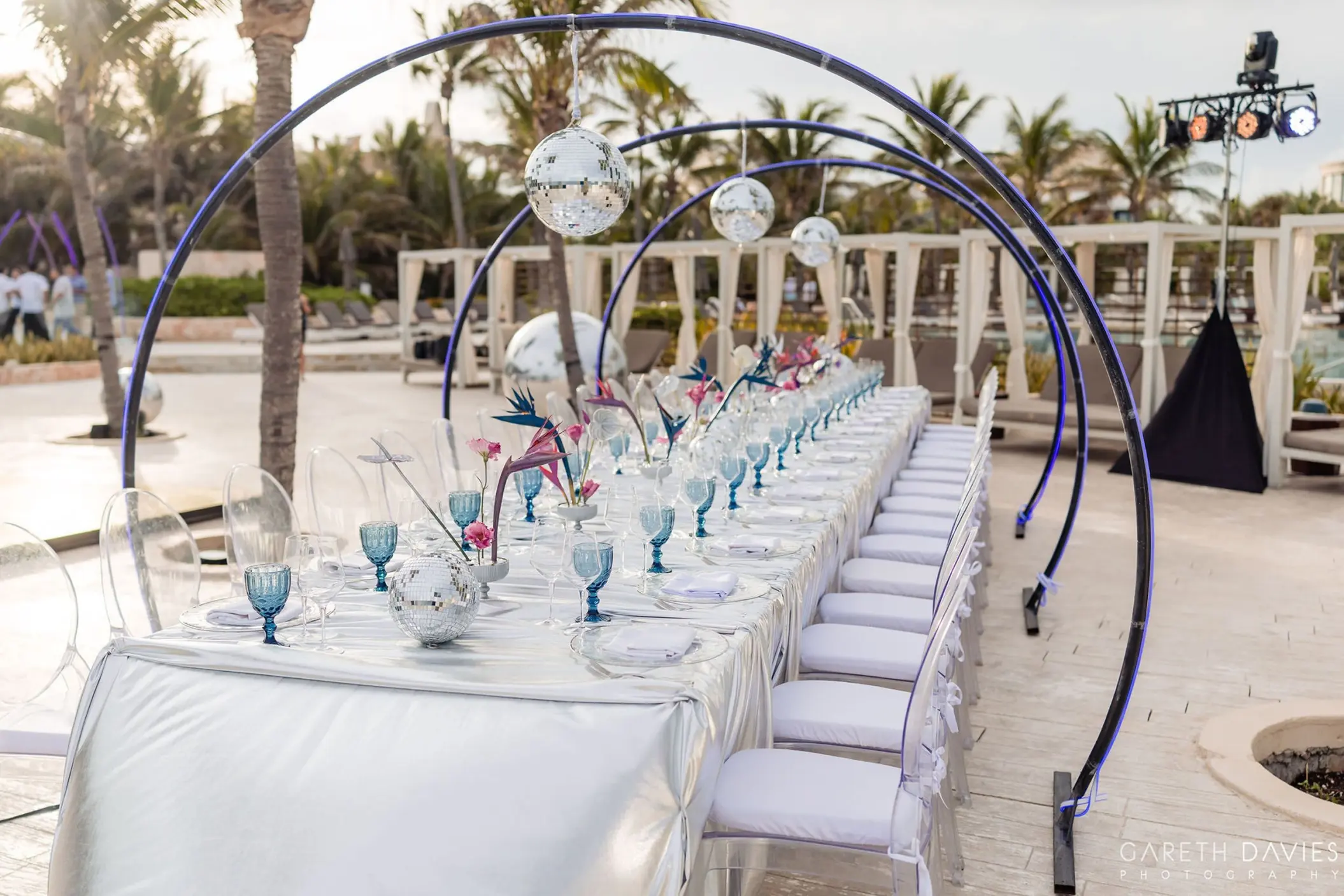 Long wedding reception table under blue hoops with disco balls at Grand Palladium Riviera Maya