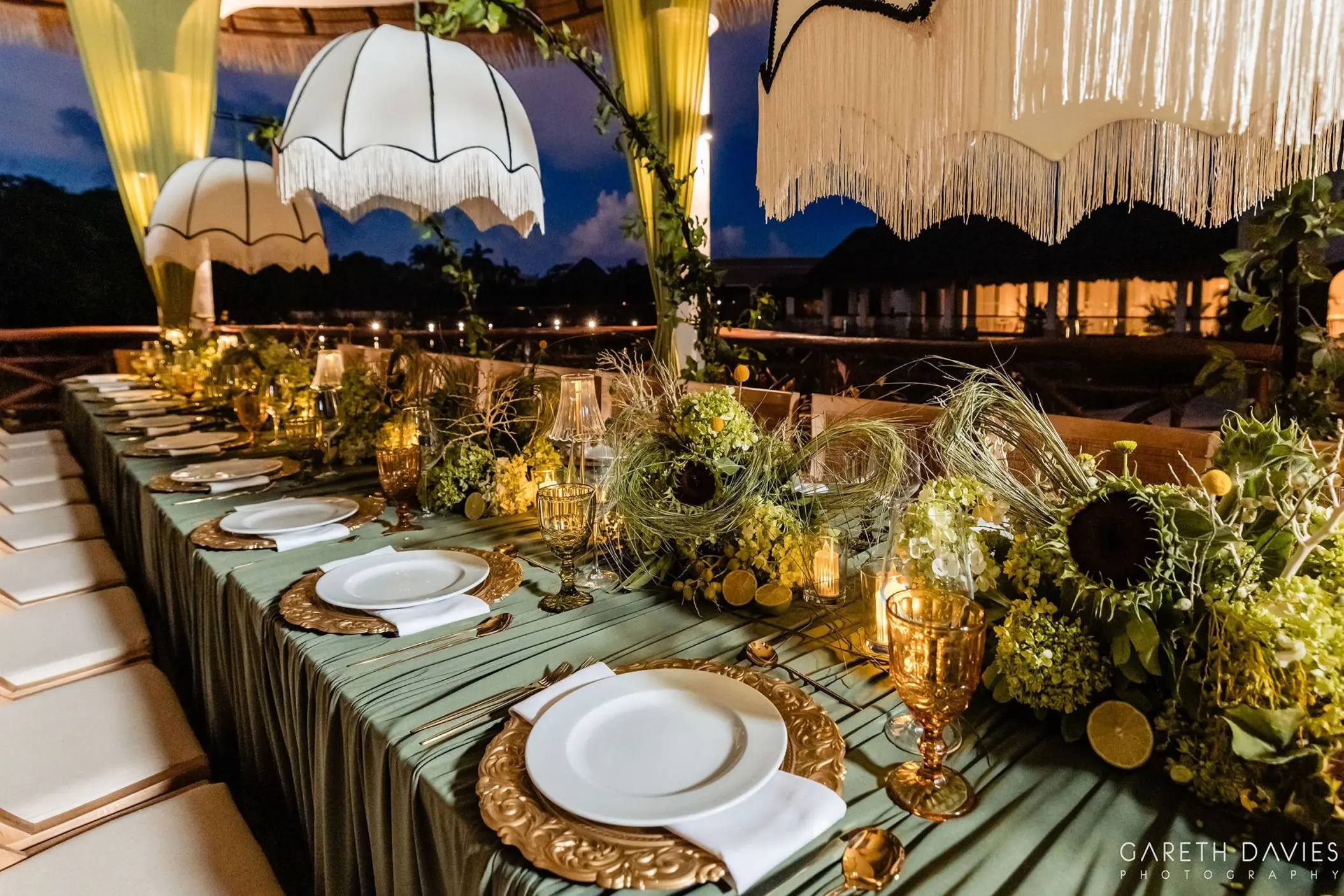 Outdoor wedding reception setup with floral centerpieces and fringe lanterns at Grand Palladium Riviera Maya