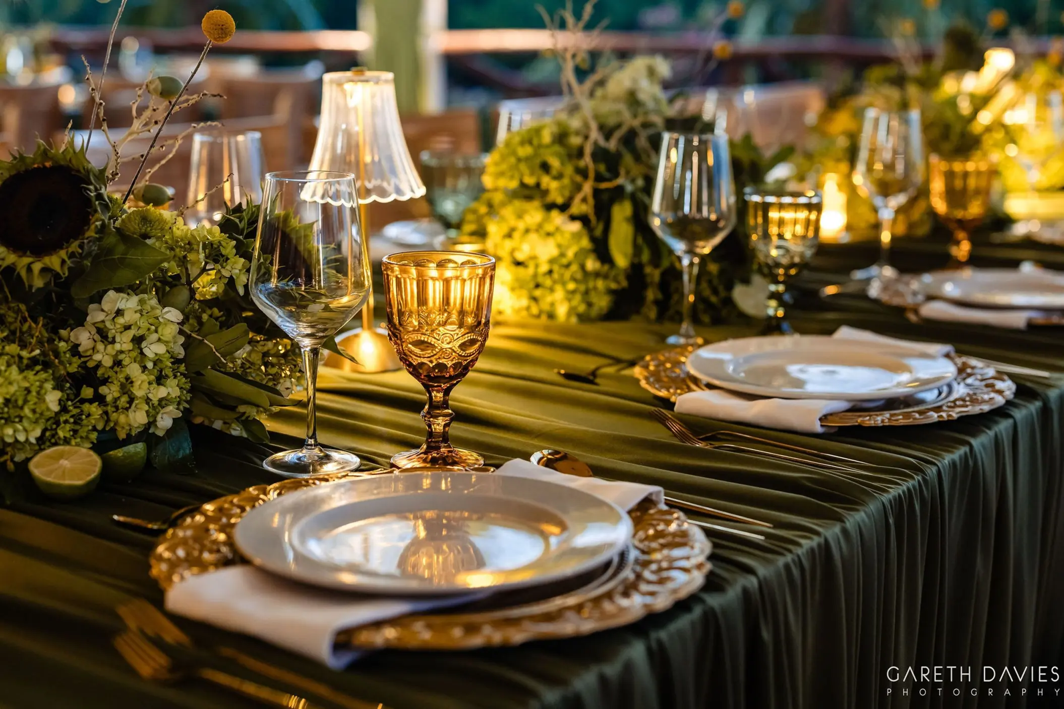 Wedding reception table with green linens, amber glassware, and floral centerpieces at Grand Palladium Riviera Maya