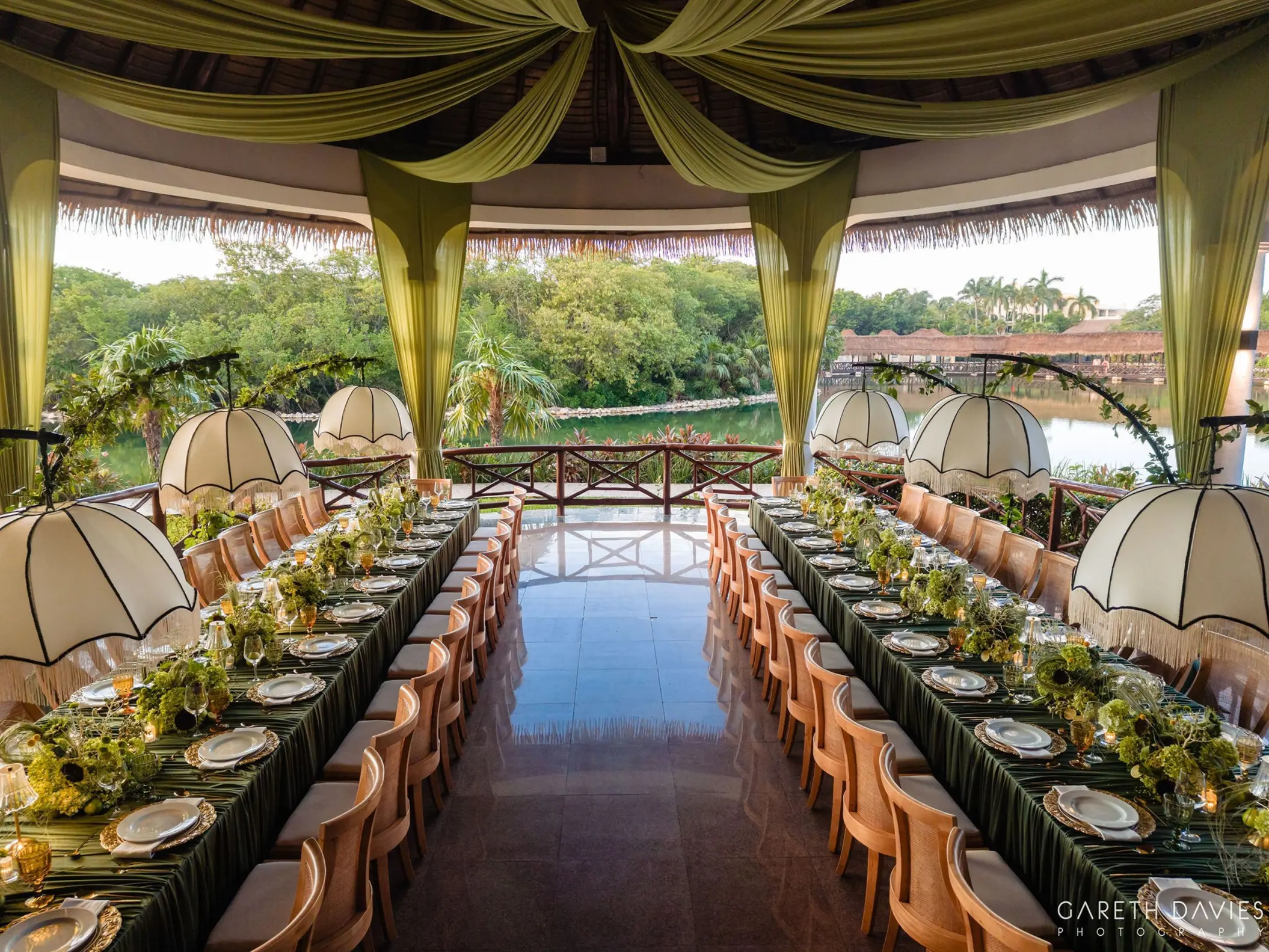 Wedding reception setup with long tables and green drapery at Grand Palladium Riviera Maya