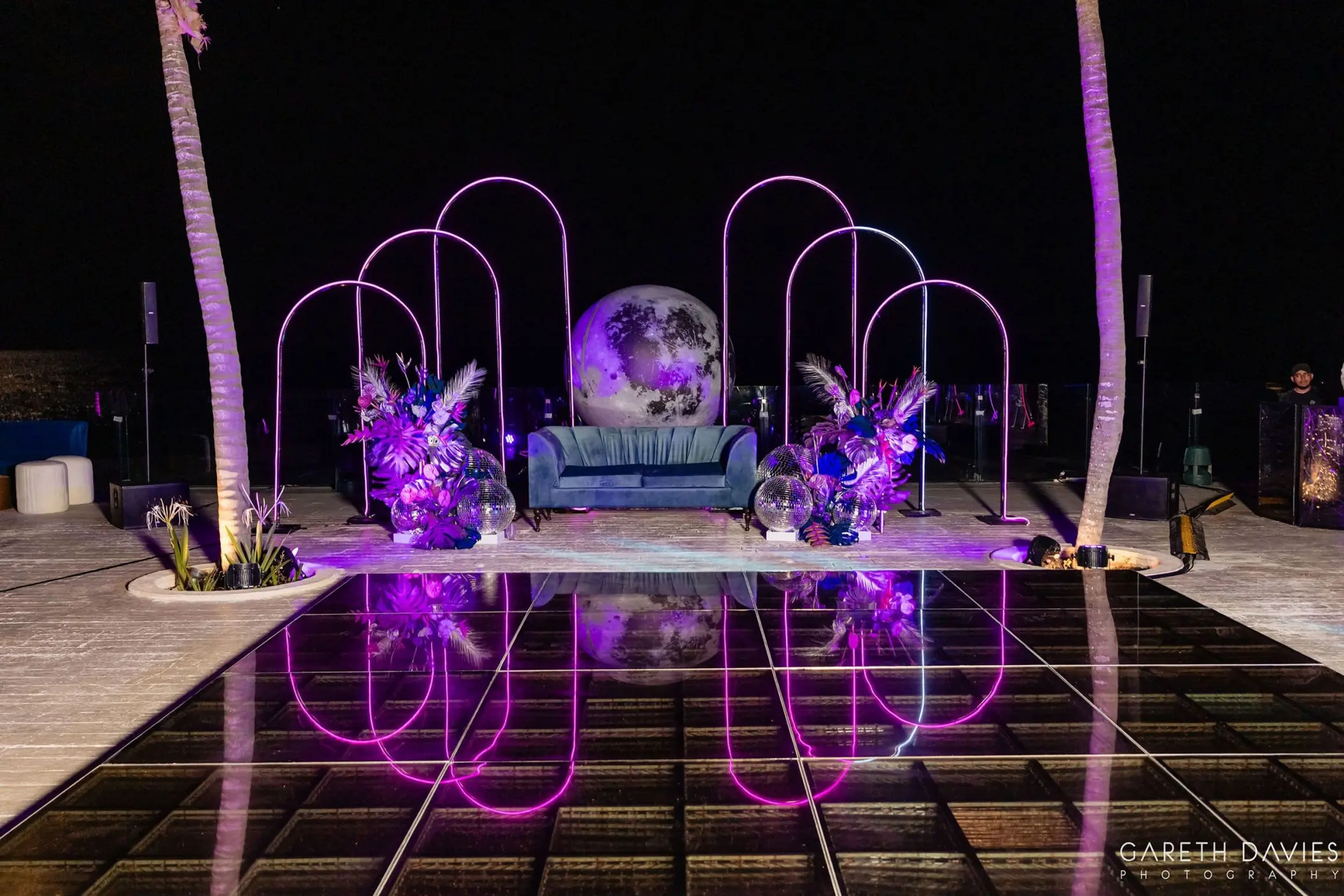 Wedding reception setup with a purple-lit dance floor and neon arches at Grand Palladium Riviera Maya