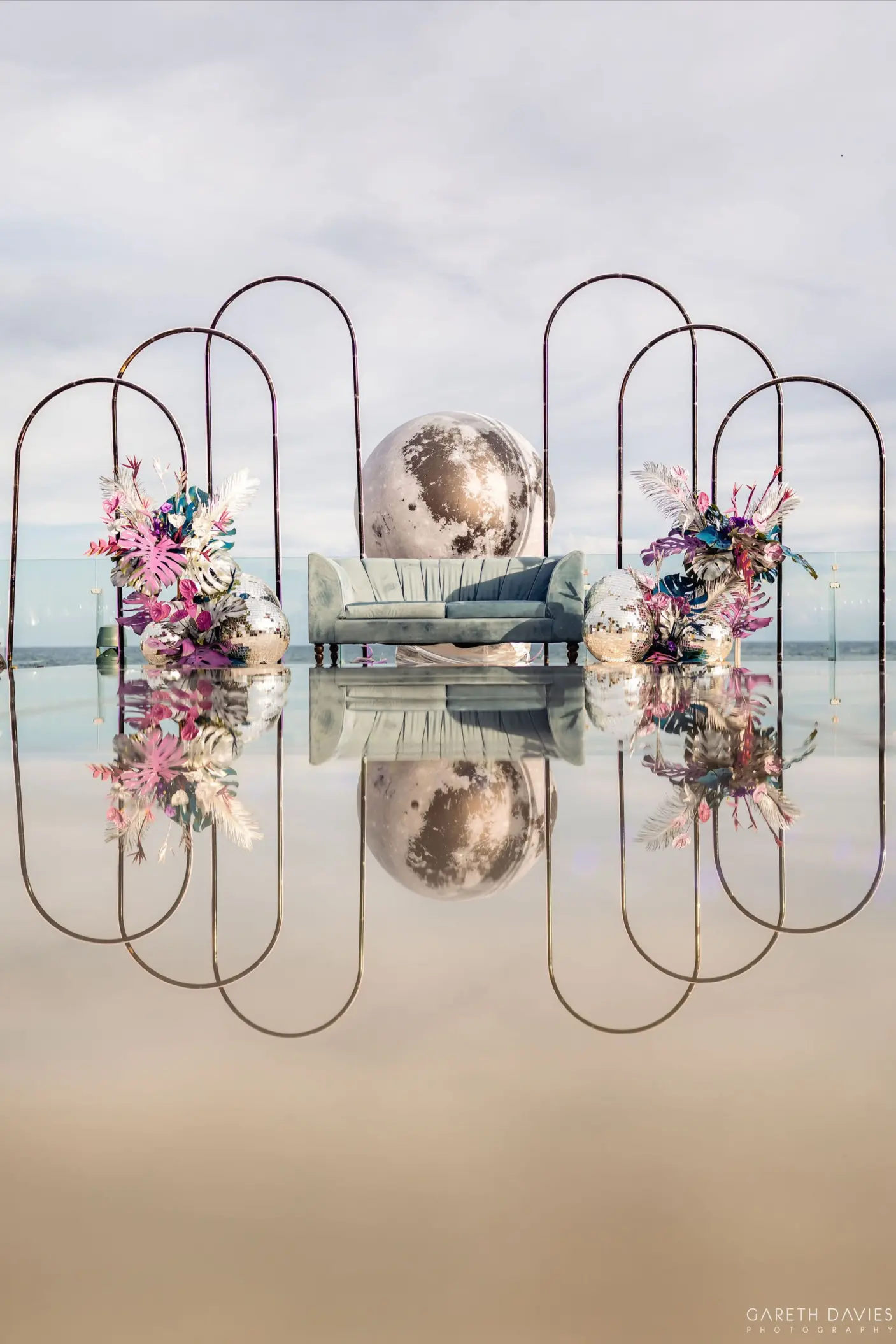Terrace wedding reception lounge with metallic arches and pink floral arrangements at Grand Palladium, Riviera Maya
