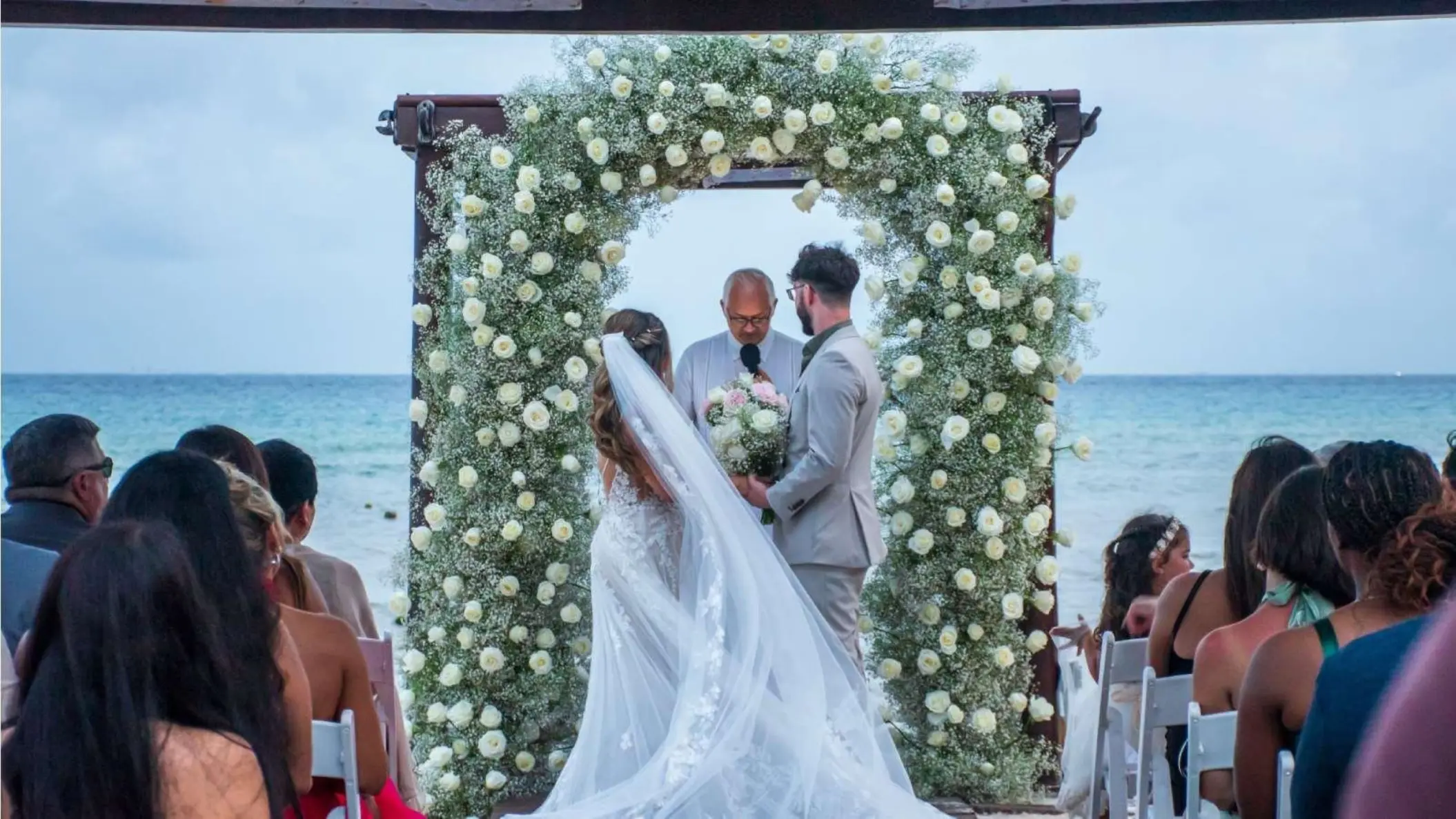 Beachfront wedding ceremony under a floral arch at Grand Riviera Princess, Playa Del Carmen