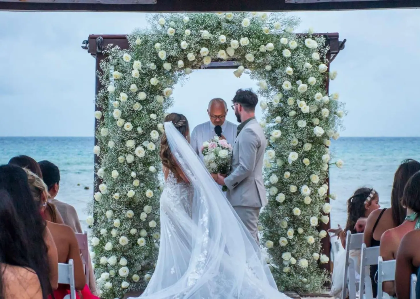 Beachfront wedding ceremony under a floral arch at Grand Riviera Princess, Playa Del Carmen